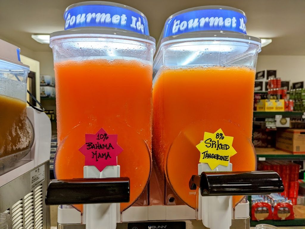 Two orange juice dispensers in a store.